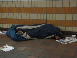 metro de Londres, un mendigo y su perro comparten un sleeping bag.